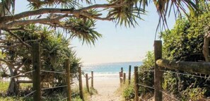 A beach path leading to the ocean, surrounded by wooden fences and tropical vegetation. - Sandy Toes and Salty Kisses - Sunshine Coast (Marcoola)
