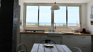 Een keuken met uitzicht op zee, een houten tafel en een hanglamp.