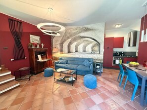 Una sala de estar con chimenea, un sofá, una mesa de centro y un comedor con sillas.