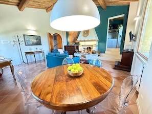 A dining area with a round wooden table, a bowl of lemons, and a large pendant light.