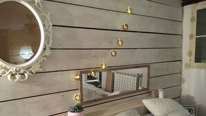Ein Schlafzimmer mit einem hölzernen Kopfende, einem beleuchteten Spiegel, einer kleinen Pflanze und einem Bett mit Kissen.