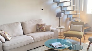 A living room with a beige sofa, a coffee table, a chair, and a staircase. - Avignon Lovely Flat (Villeneuve-lès-Avignon)