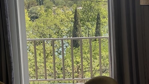A balcony with a glass table and chairs, overlooking a lush green landscape and historic buildings. - Avignon Lovely Flat (Villeneuve-lès-Avignon)