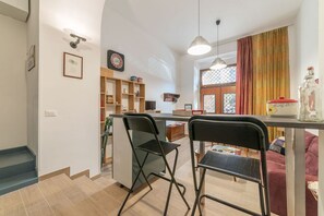 A kitchen with a dining area, a clock, and a window with curtains.