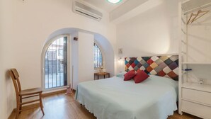 A bedroom with a bed, a chair, a wardrobe, and a window. - GuestHost - Cozy one bedroom apartment of about 55 sqm located on the ground floor of a building that can accommodate up to 4 people, perfect for visiting the wonders of the Eternal City! Just 100 meters far there is the stop of several urban bus lines,  (Roma)