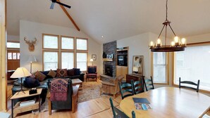 A spacious living room with a fireplace, a dining area, and a kitchen. - Rustic Retreat with Access to Exclusive Golf (Sunriver)