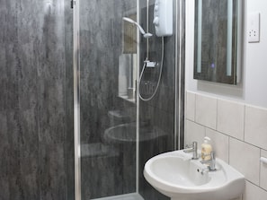 A modern bathroom with a glass shower enclosure, a white sink, and a mirror above it.