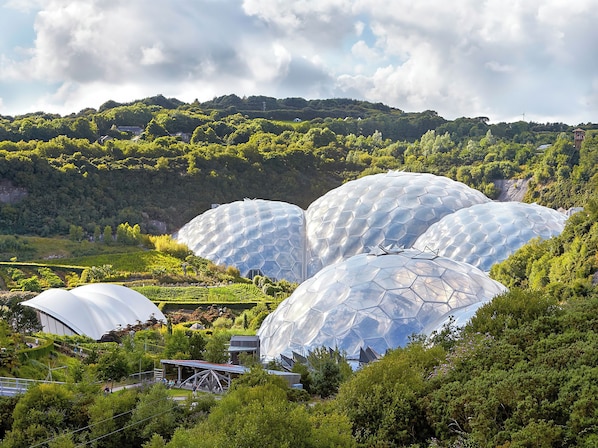 A large, dome-shaped building complex surrounded by lush greenery and hills.