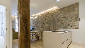 Una cocina moderna con pared de piedra, suelo de madera y un comedor con sillas y mesa.