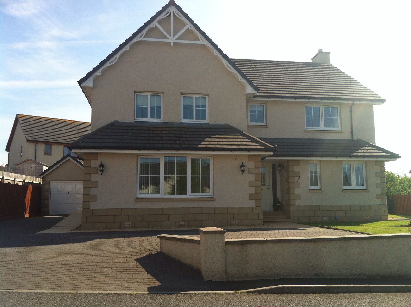 A two-story house with a gabled roof, a front garage, and a paved driveway.