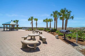 Relax in a communal patio area with stone tables and benches, a gazebo, and barbecue grill.