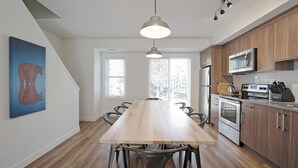 A modern kitchen with a wooden table, black chairs, a microwave, and an oven. - Basecamp Resorts Canmore I Two Bedroom Apartment, Dog Friendly (Canmore)