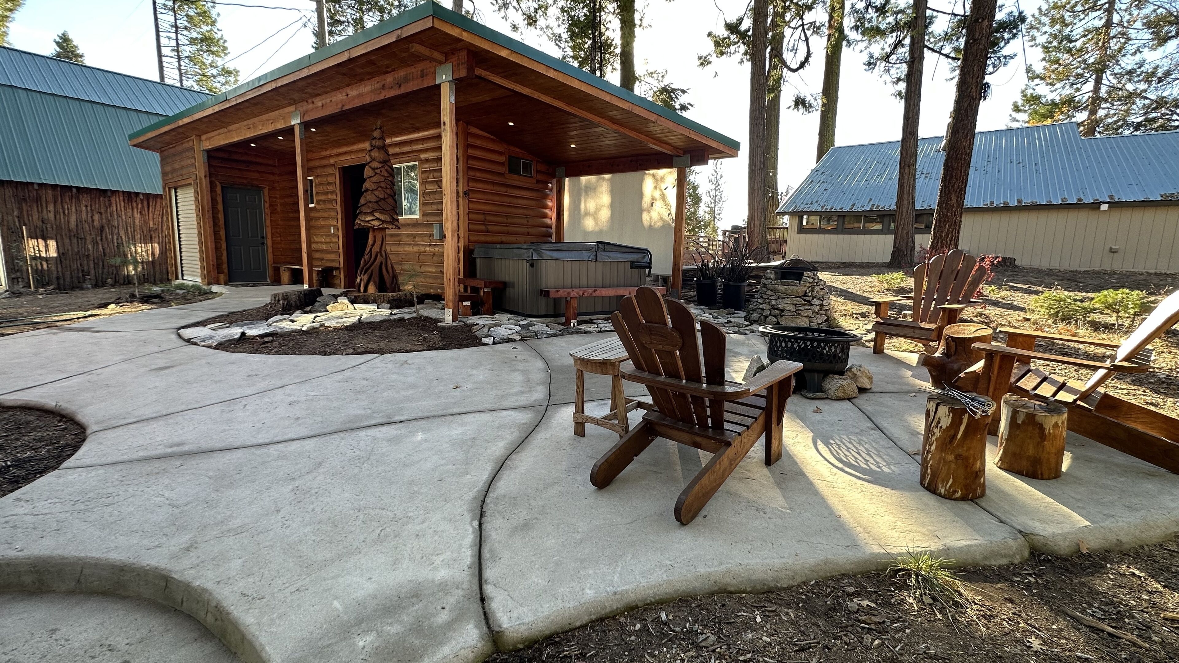 Una cabaña de madera con porche cubierto, mobiliario exterior y un hogar de piedra.