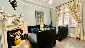 A bedroom with a fireplace, two beds, a large window with curtains, and a decorative angel wall piece. - Pet Friendly - Elwood Eclectic Gem Walk to St Kilda beach - Flexible Home offering 4 or 6 Bedrooms. (Elwood)