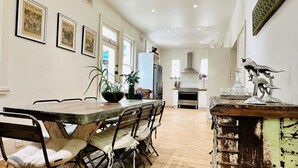 A spacious kitchen with a long counter, a dining area with chairs, and a decorative metal sculpture. - Pet Friendly - Elwood Eclectic Gem Walk to St Kilda beach - Flexible Home offering 4 or 6 Bedrooms. (Elwood)