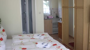 Quarto com cama, guarda-roupa de madeira e banheiro visível por uma porta aberta.