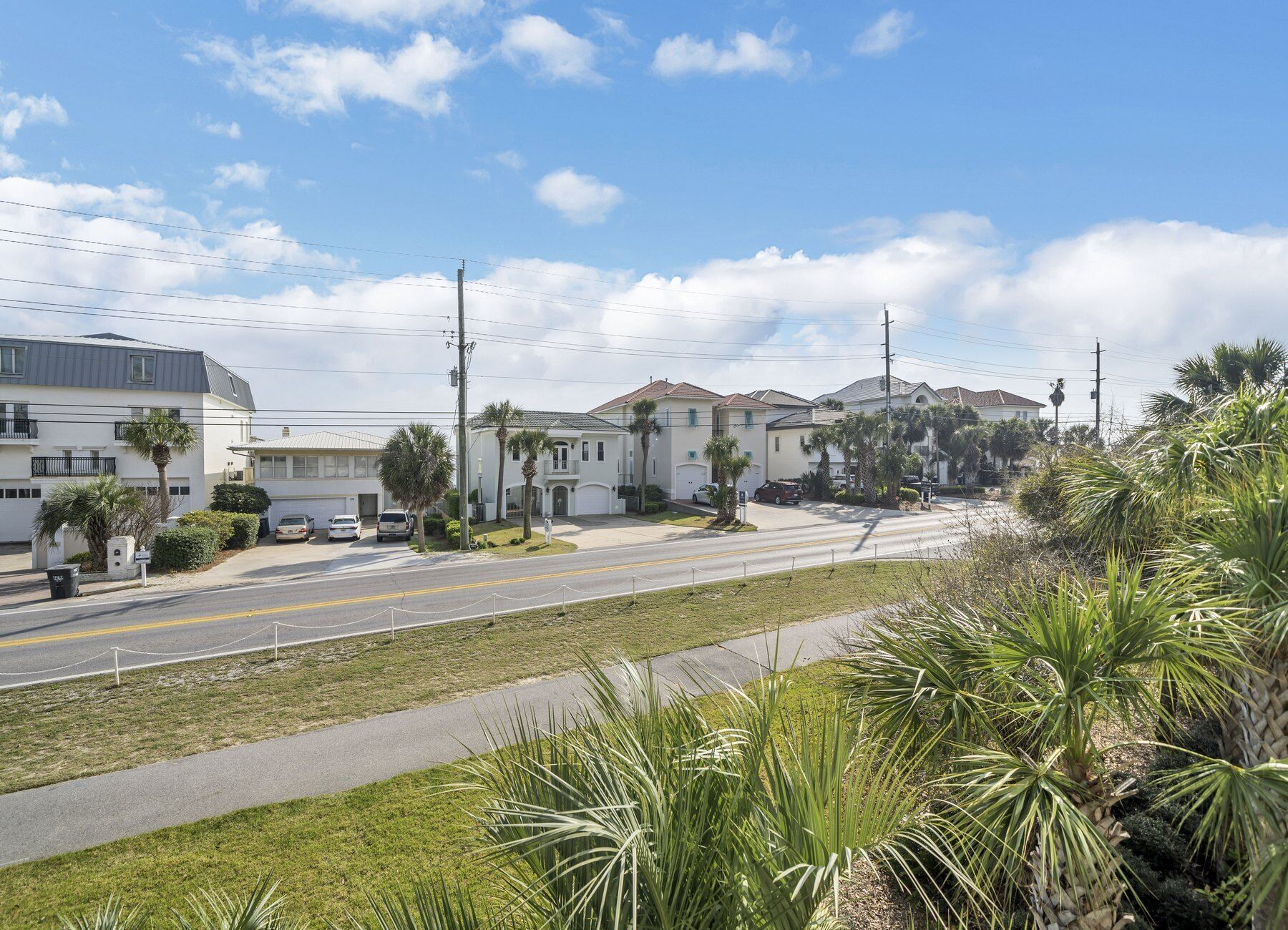 A residential street with houses, a clear sky, and a sidewalk.