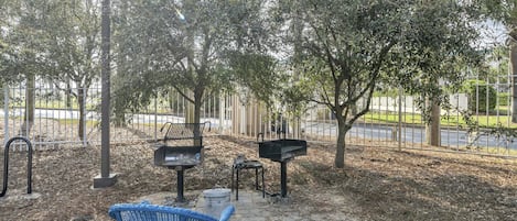Un parc doté d’une allée pavée, de bancs en métal et d’un fauteuil tressé aux couleurs bleu et rouge.