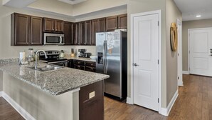Una cocina moderna con encimeras de granito, electrodomésticos de acero inoxidable y gabinetes de madera oscura.