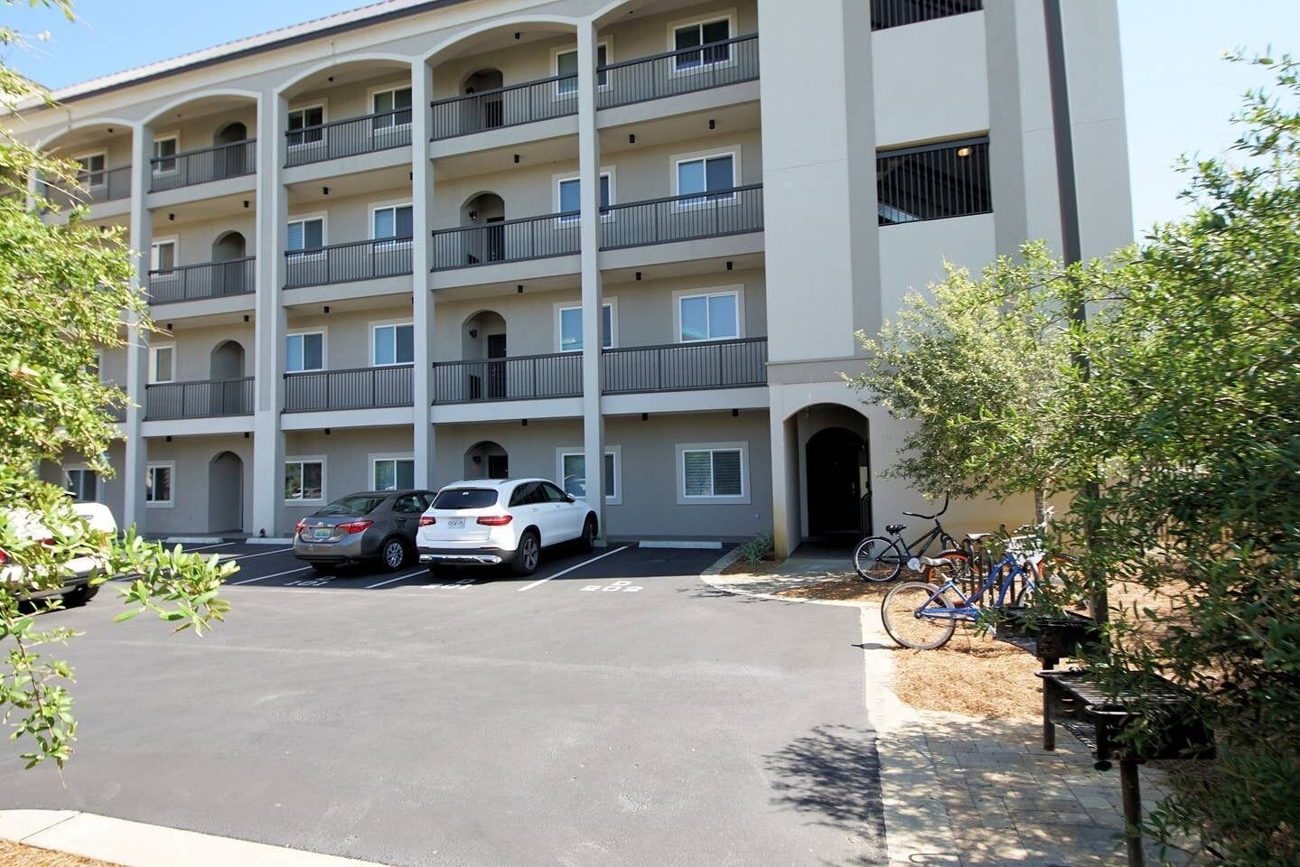 A multi-story apartment building with a parking lot in front.