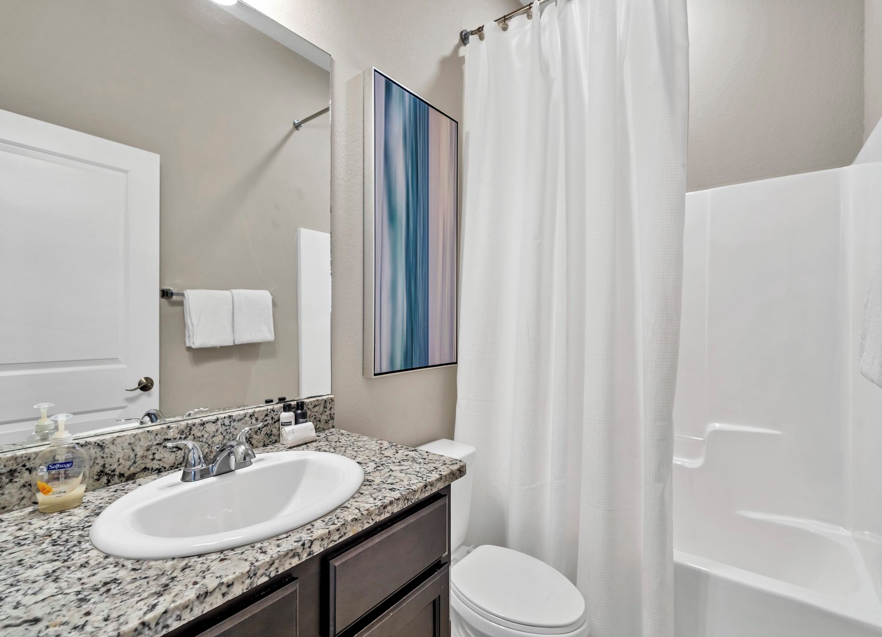 A bathroom with a white sink, a mirror, a shower curtain, and a toilet.