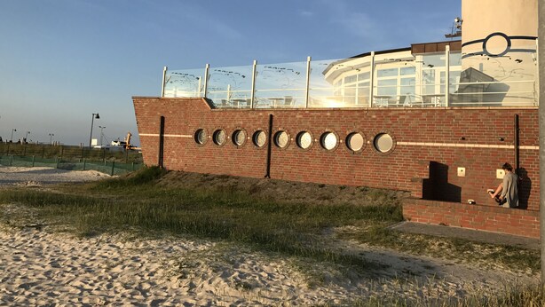 Un edificio con fachada de ladrillo, ventanas circulares y una sección superior de vidrio.
