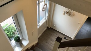 Una escalera conduce a una plataforma con vista a un jardín a través de una ventana.