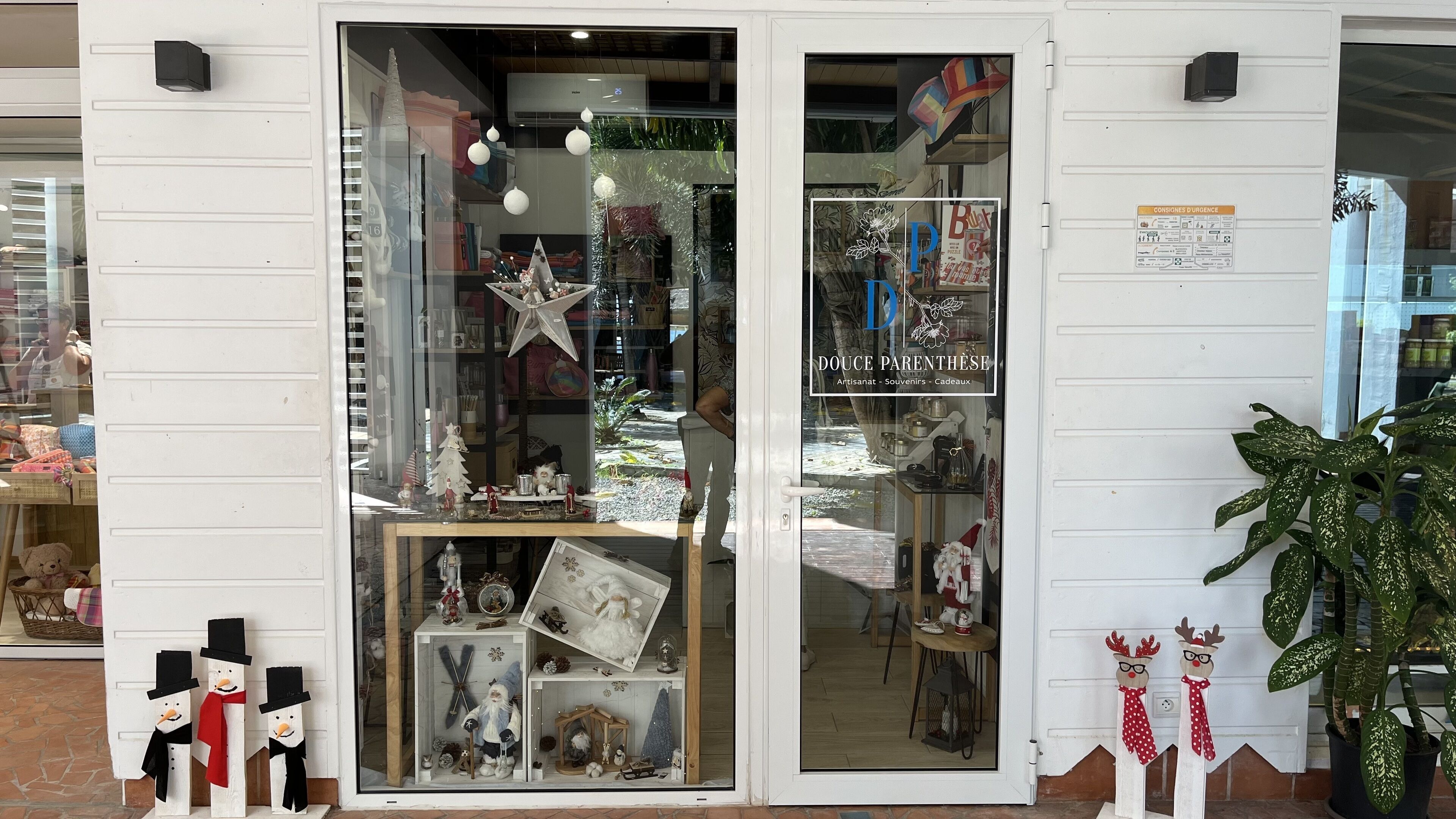 A storefront with a glass door, displaying various items like a Christmas tree, a star, and a reindeer figure.