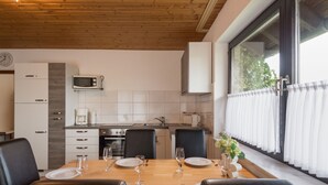 Een moderne keuken met witte kastjes, een magnetron en een eettafel gedekt voor vier personen.