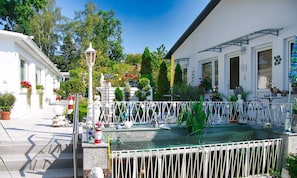 Une cour avec une fontaine, une balustrade blanche et diverses statues.