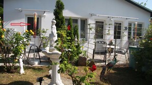 Un edificio bianco con un giardino antistante, che include una statua, un pavone e una fontana.