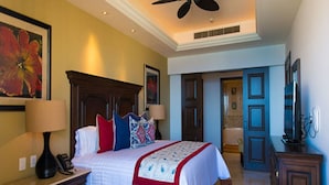 A hotel room with a large bed, a wooden headboard, a desk with a lamp, and a television. - LUXURIOUS PRESIDENTIAL suite 2 bedroom 3 baths (Cabo San Lucas)