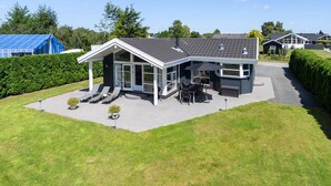 A modern house with a covered patio, a dining area, and a large window overlooking the yard. - Awesome home in Haderslev with kitchen (Haderslev)