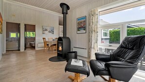 A cozy living room with a wood-burning stove, a leather chair, and a dining area with a table and chairs. - Awesome home in Haderslev with kitchen (Haderslev)