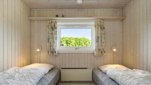 A room with two beds, a window with curtains, and a wall-mounted heater. - Awesome home in Haderslev with kitchen (Haderslev)