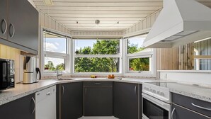 A modern kitchen with dark cabinets, a large window, and a view of greenery. - Awesome home in Haderslev with kitchen (Haderslev)