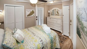 Un dormitorio con una cama, un ventilador de techo, un aparador y un cuadro.