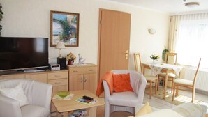 A living room with a television, a table, and two chairs. - Vacation apartment 1 - Ferienanlage Bräuning (Binz)