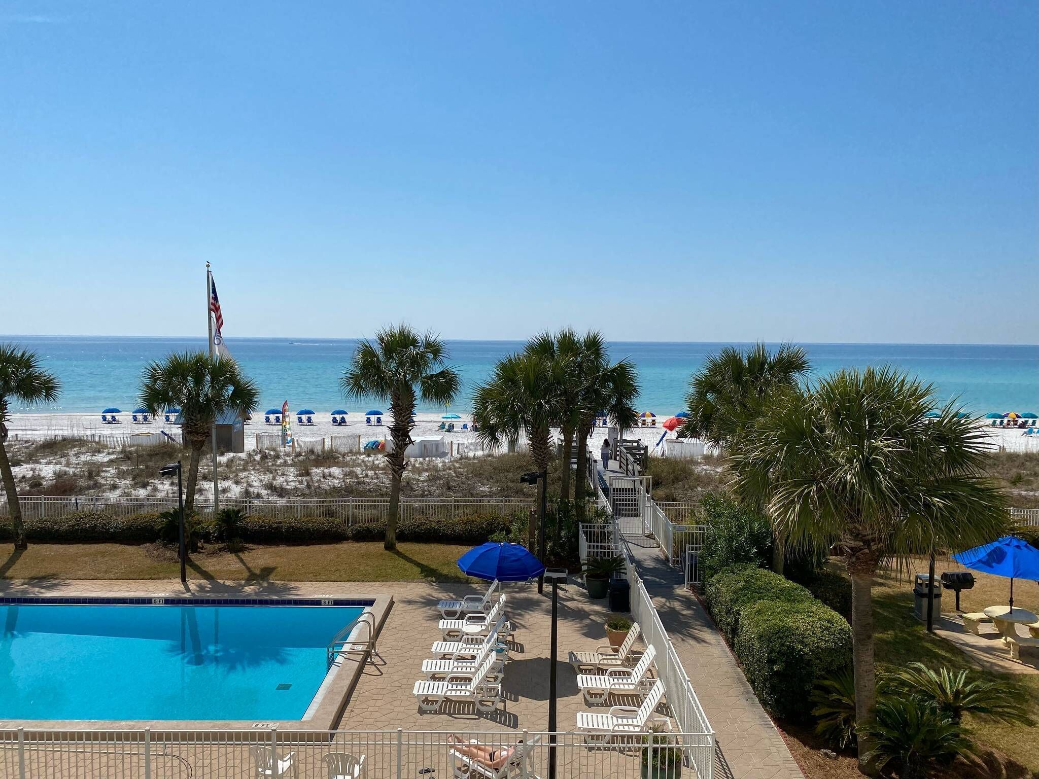 Ein Poolbereich mit Liegestühlen und Blick auf den Strand.