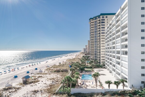 A beachfront hotel with a pool, beach umbrellas, and a clear view of the ocean.