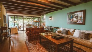Una sala de estar acogedora con techo de madera, un ventanal grande y un tablero de ajedrez sobre la mesa de centro.