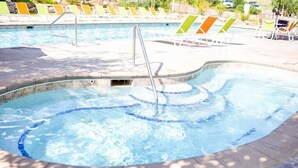 Una piscina con una scala in metallo e lettini intorno.