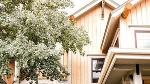 Una casa a due piani con un portico, una porta in legno e un piccolo angolo relax all'aperto.