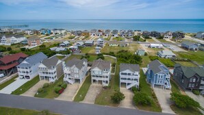 A coastal residential area with multiple two-story houses, a pier in the background, and a clear view of the ocean. - Sandy Bottoms: Oceanside, Pool, Spa, Dogs OK (Nags Head)