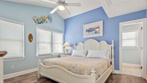A bedroom with a bed, a ceiling fan, a nightstand, a lamp, and a window with blinds. - Sandy Bottoms: Oceanside, Pool, Spa, Dogs OK (Nags Head)