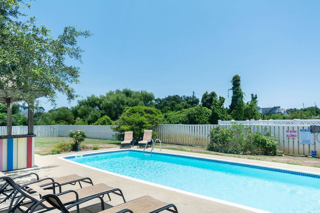 A swimming pool with lounge chairs and a wooden deck.
