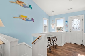A room with a staircase, a white door with a glass window, and a view of the outdoors. - Sandy Bottoms: Oceanside, Pool, Spa, Dogs OK (Nags Head)