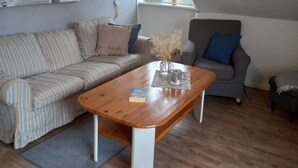 Una sala de estar acogedora con un sofá a rayas, una mesa de centro de madera y un sillón gris.