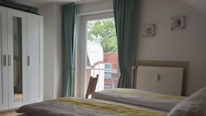 Un dormitorio con cama, radiador y ventana con cortinas.