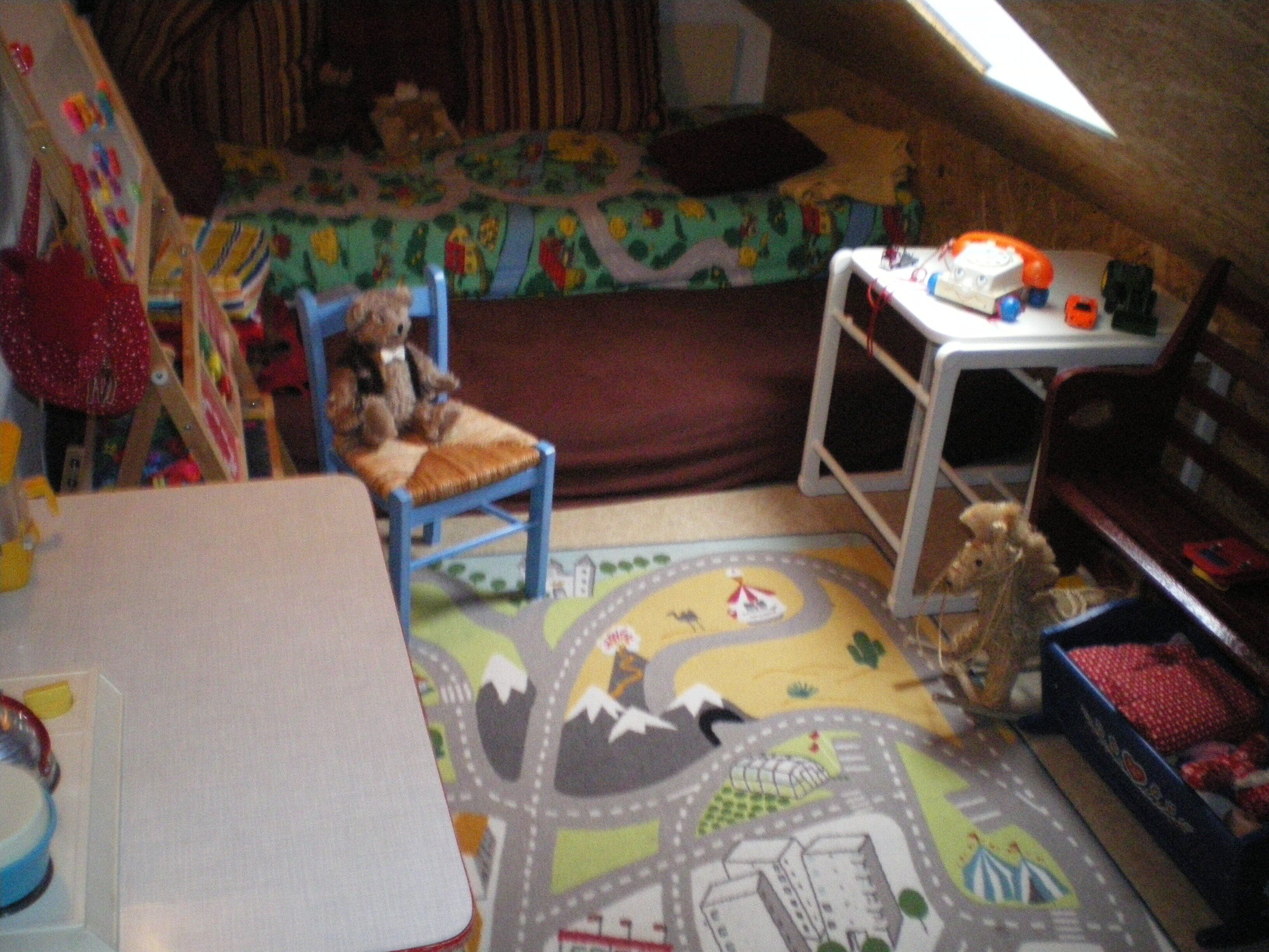 Ein Kinderzimmer mit Bett, Spielzeug und einer Krabbeldecke.